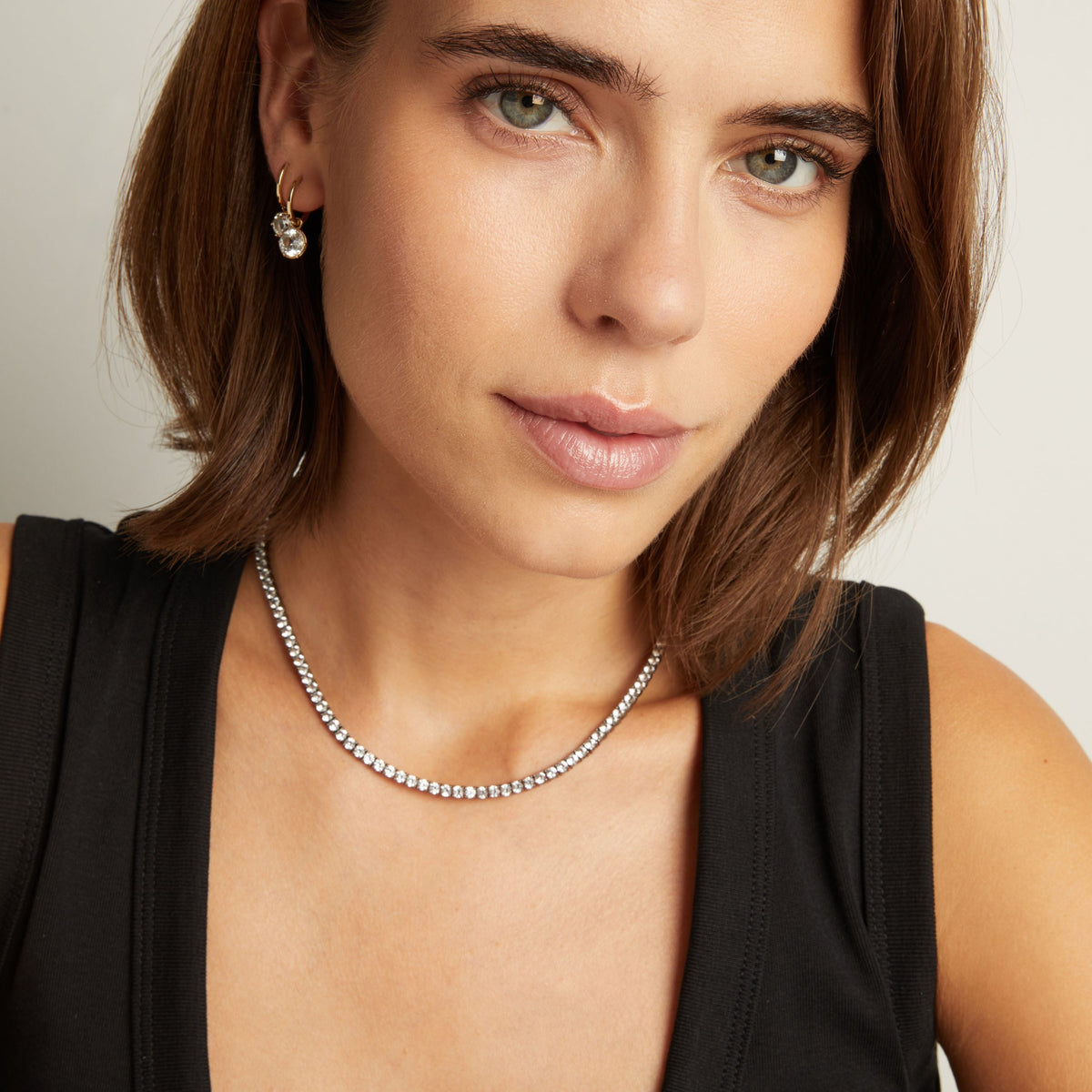 Model. Close up of woman wearing a Black Rhodium Tennis Necklace on neutral background.