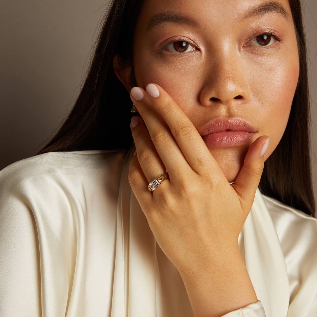 Model. Woman wearing a diamond ring with a neutral background