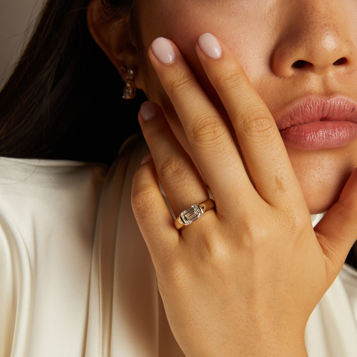 Model. Close-up of a woman's hand wearing a diamond ring with a neutral background