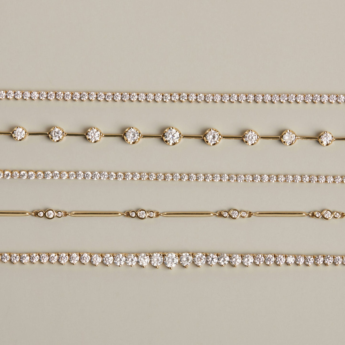 Model. Five gold and diamond bracelets of different shapes on neutral background