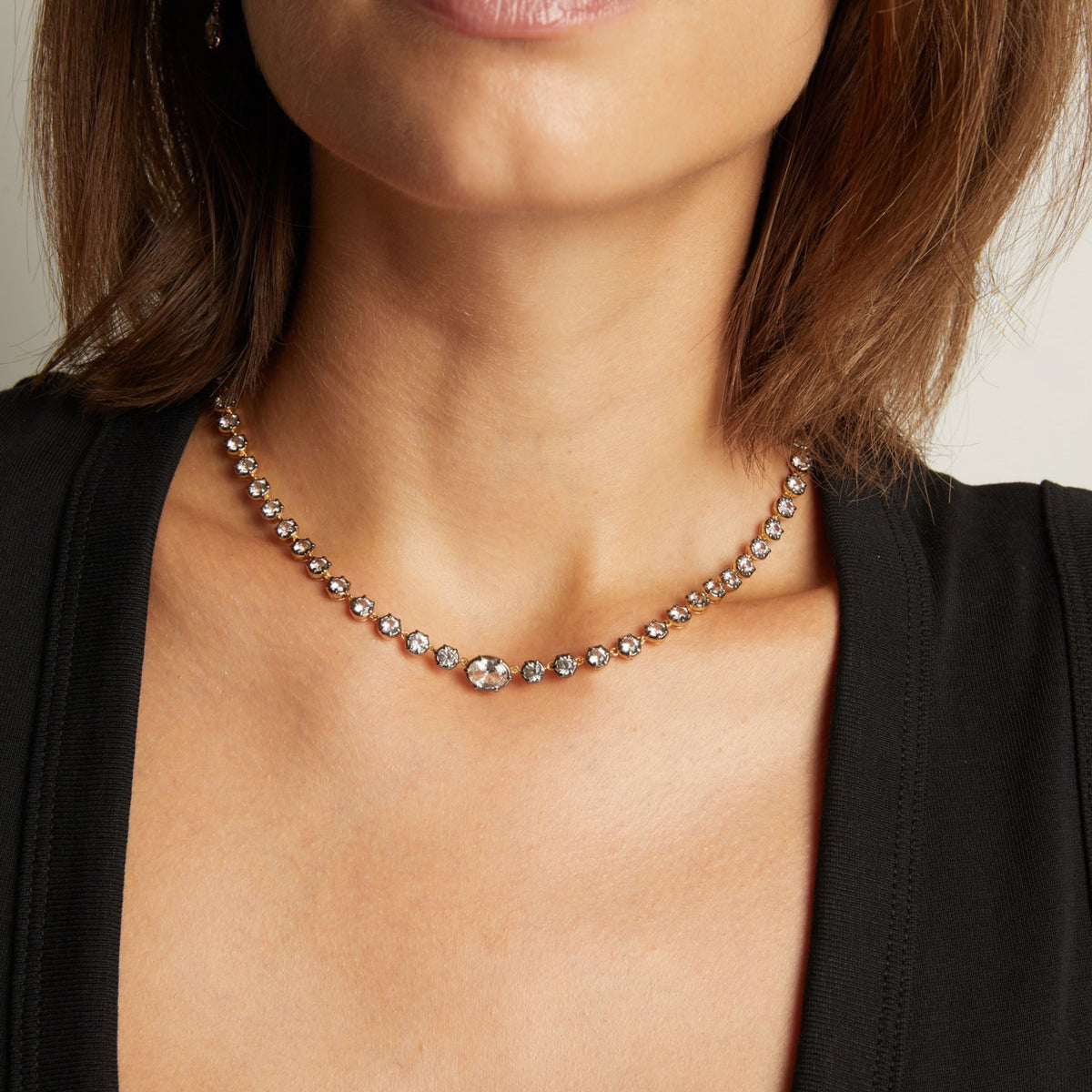 Model. Close up of a woman in a black top wearing a Georgian set tennis necklace on neutral background.