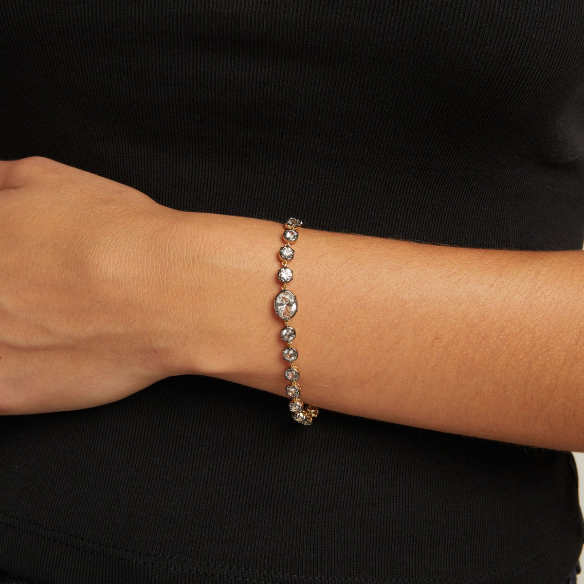 Model. Close up of a woman in a black top wearing a Georgian set tennis bracelet on neutral background.