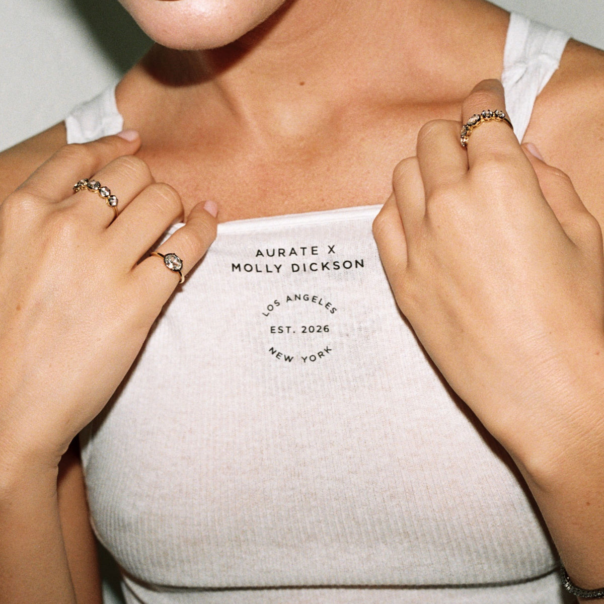 Model. Close up of woman wearing white tank top with lots of jewelry on.
