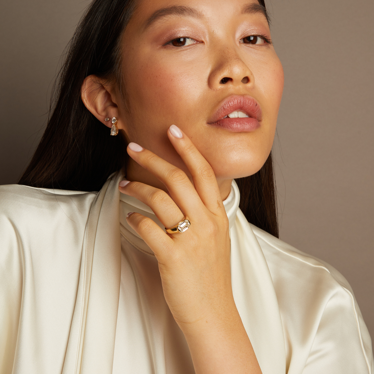 Model. Woman wearing a diamond ring and earrings against a neutral background