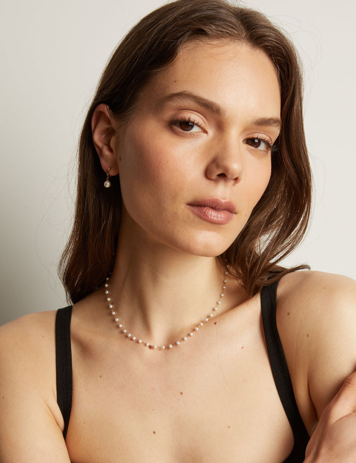 Model. Pearl necklace worn by a person with a neutral background.