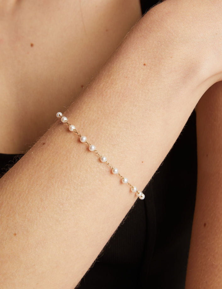 Close up of a pearl bracelet on woman with neutral background.