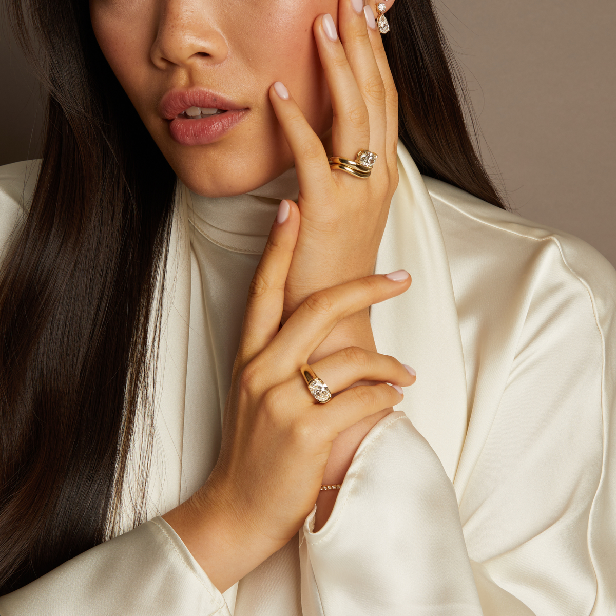 Model. Woman wearing two diamond rings on a neutral background