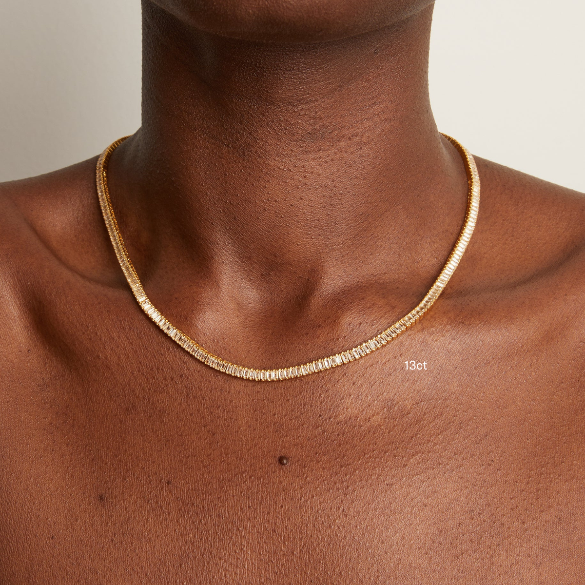 Model. Gold necklace on a person's neck with a neutral background