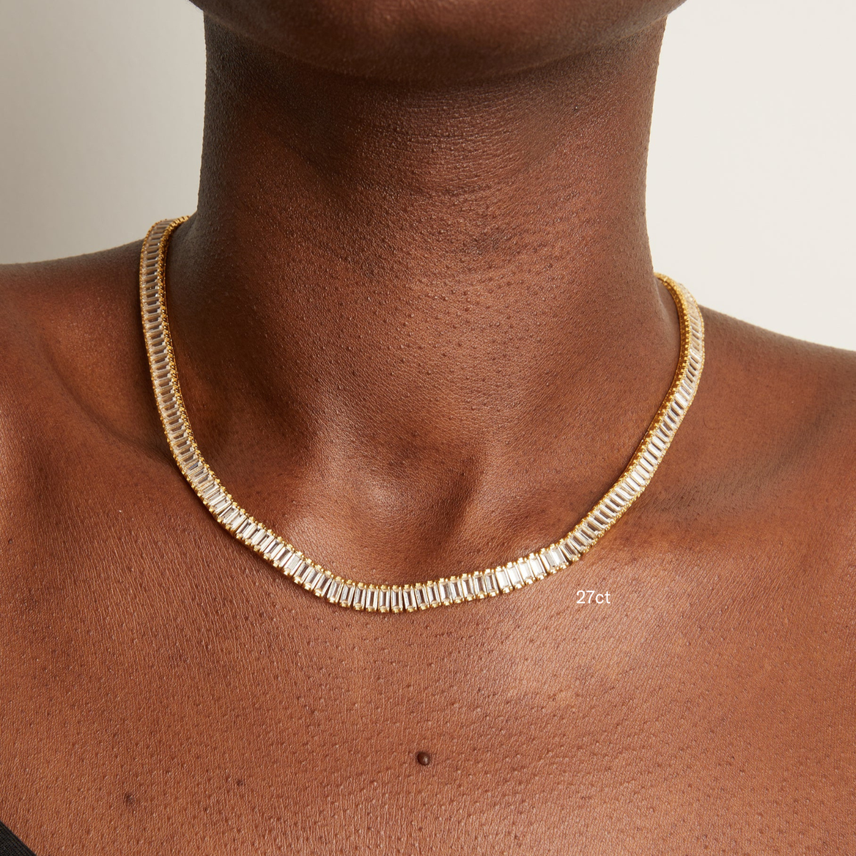 Model. Gold necklace on a person's neck with '27ct' text