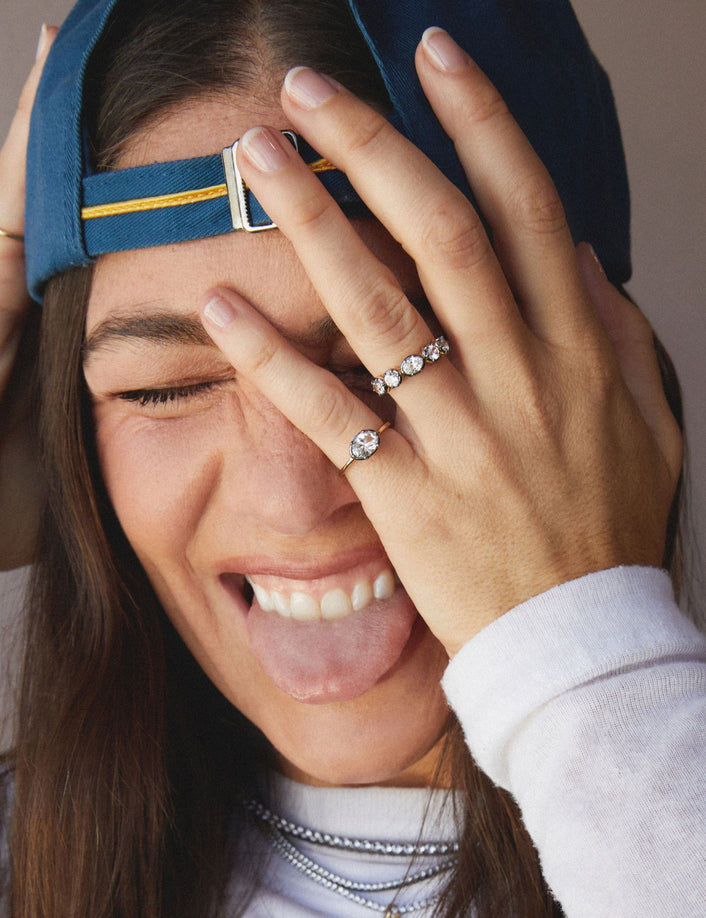 Close up of woman wearing two rings with her hand over her face and tongue out. 