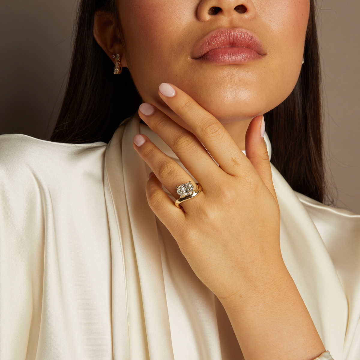 Close-up of a woman's hand with a gold ring, wearing a white garment.