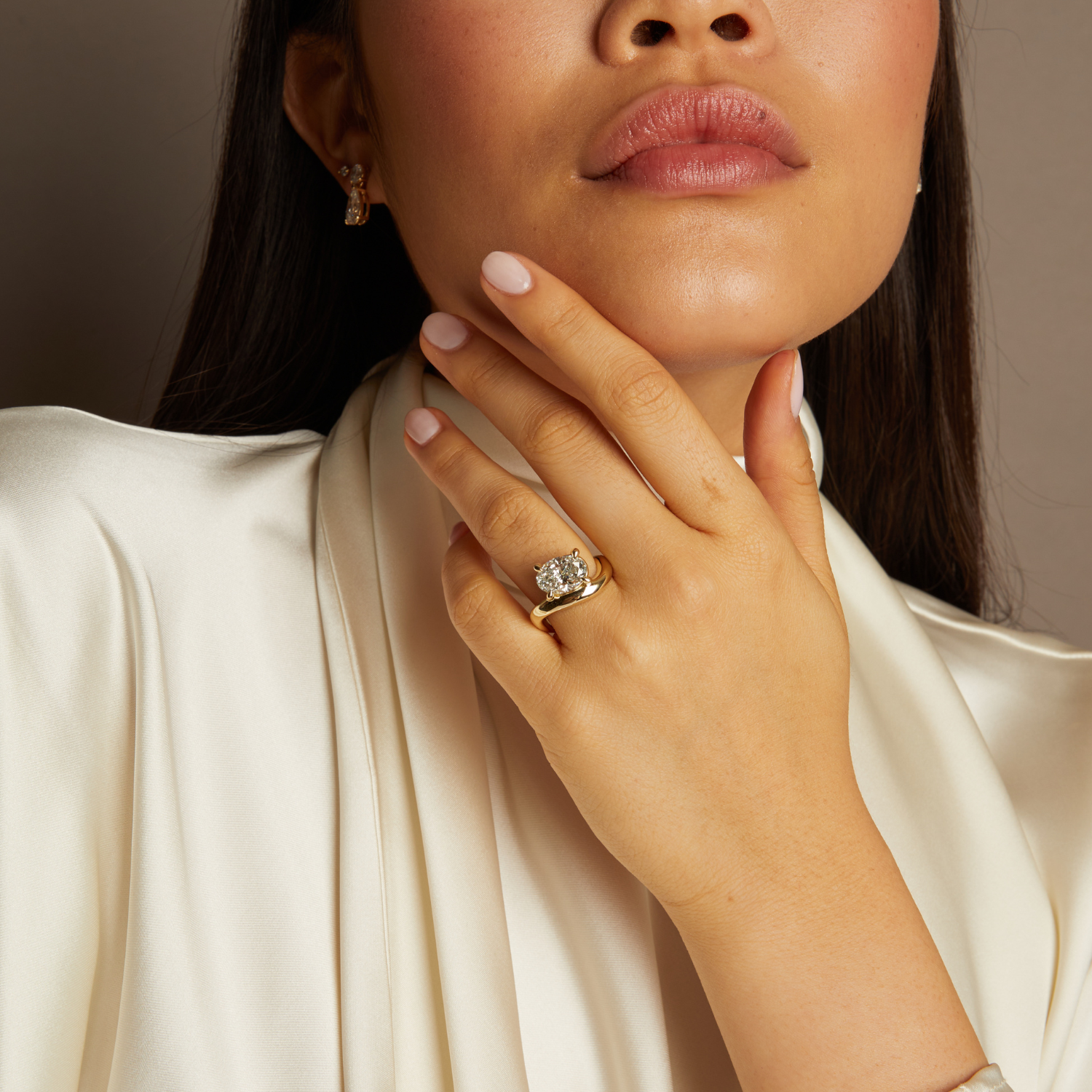 Close-up of a woman's hand with a gold ring, wearing a white garment.