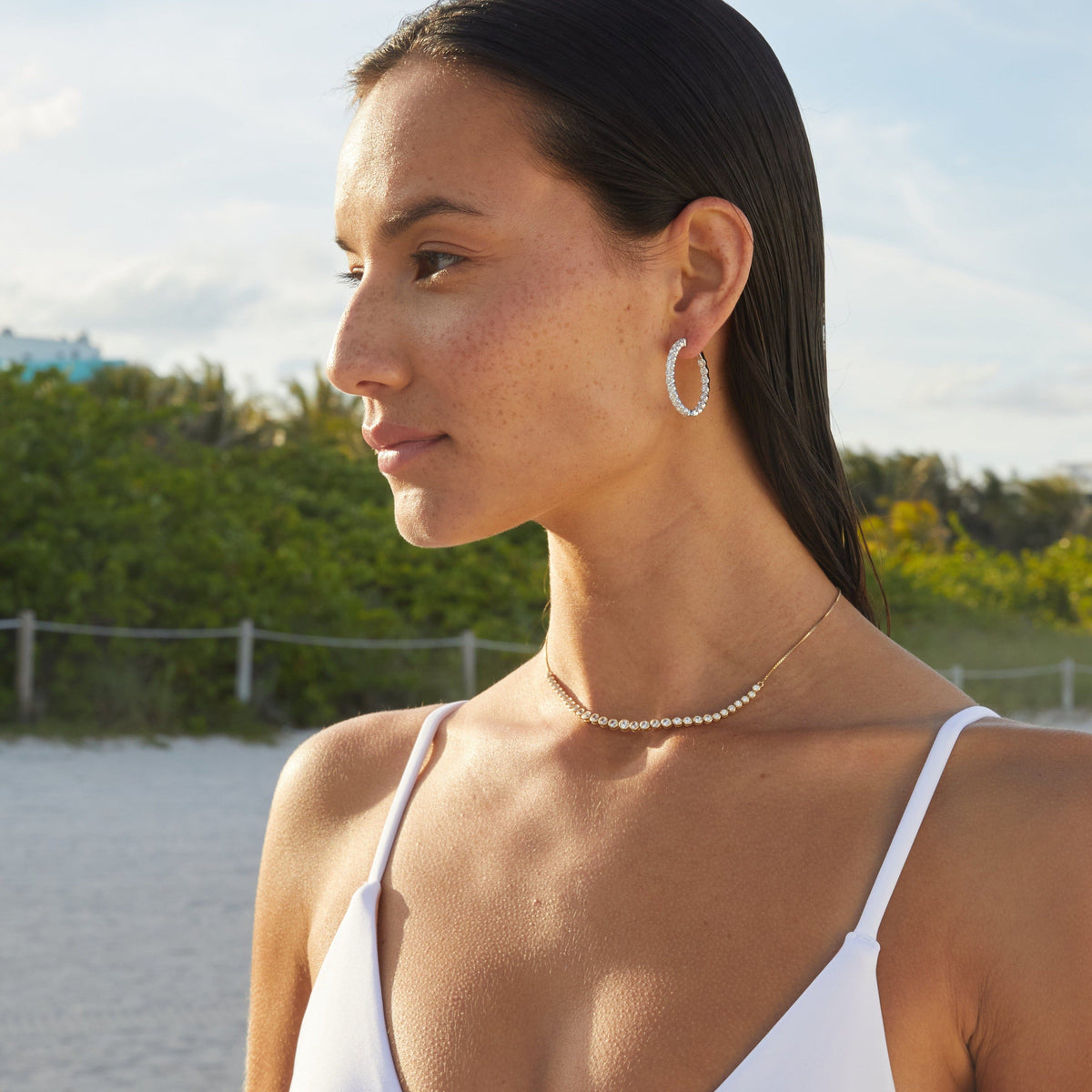 Lifestyle Model woman wearing diamonds on a gold chain and a hoop earring 