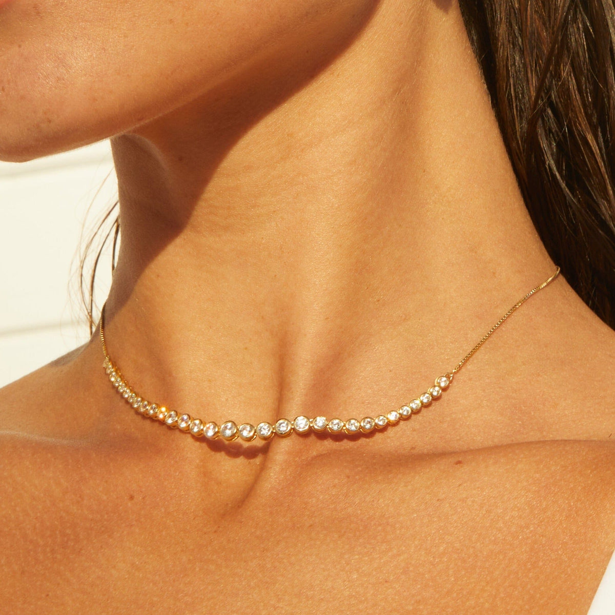 Model. Woman wearing a gold chain necklace with stones 