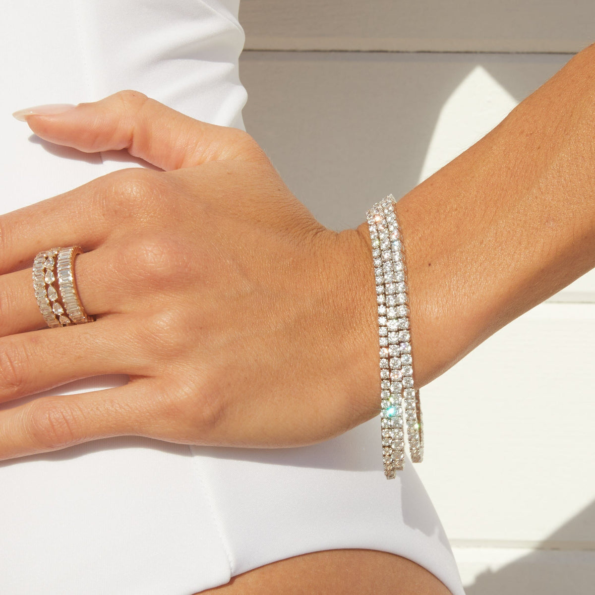 Lifestyle Model close up of woman wearing three diamond tennis bracelets and three diamond rings 