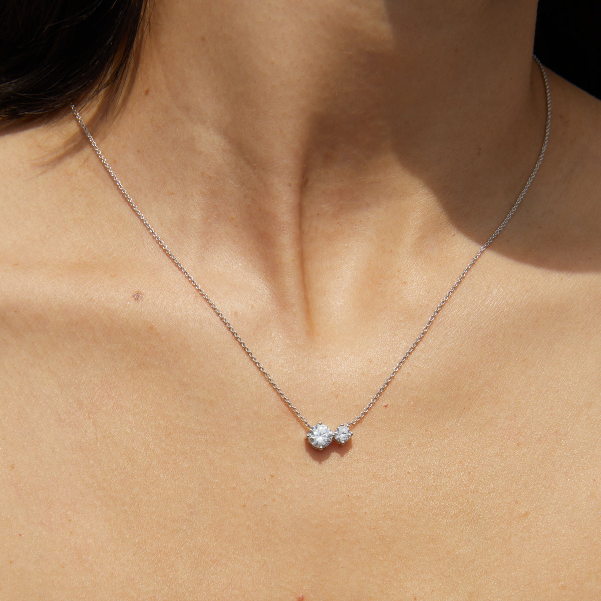 Model.  close up of woman wearing a necklace with two diamonds 