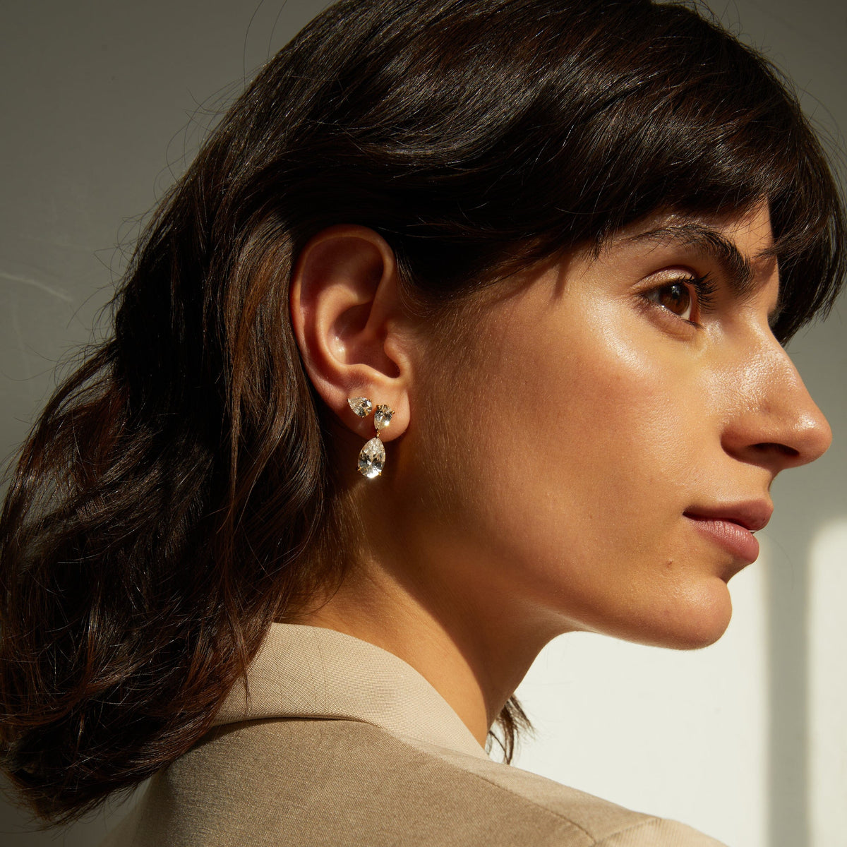 Model. Side profile of woman wearing a diamond drop earring 