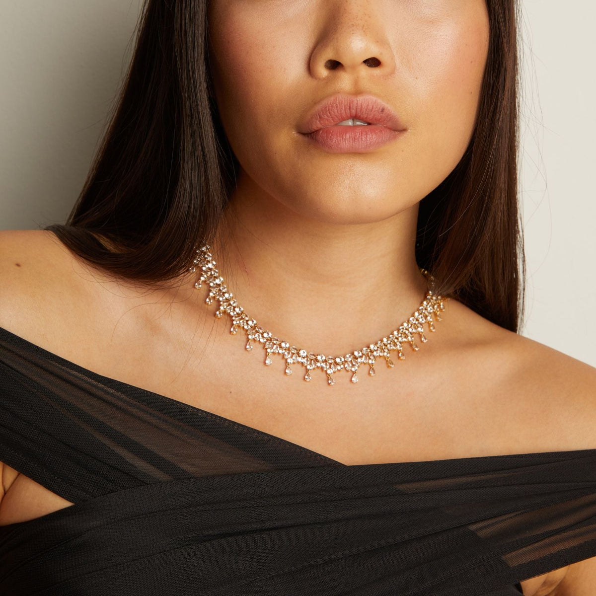 Model. Woman wearing a gold necklace with a plain background