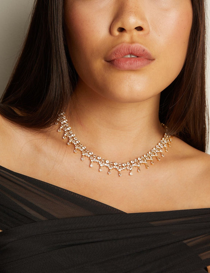 Woman wearing a gold necklace with a plain background