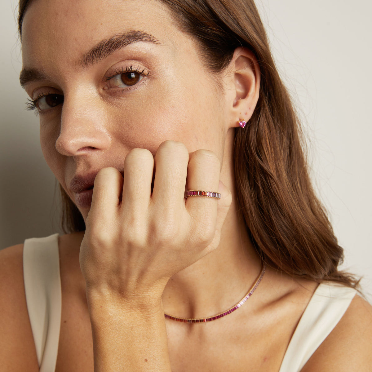 Model. Woman wearing a red gemstone ring and necklace, with a neutral background