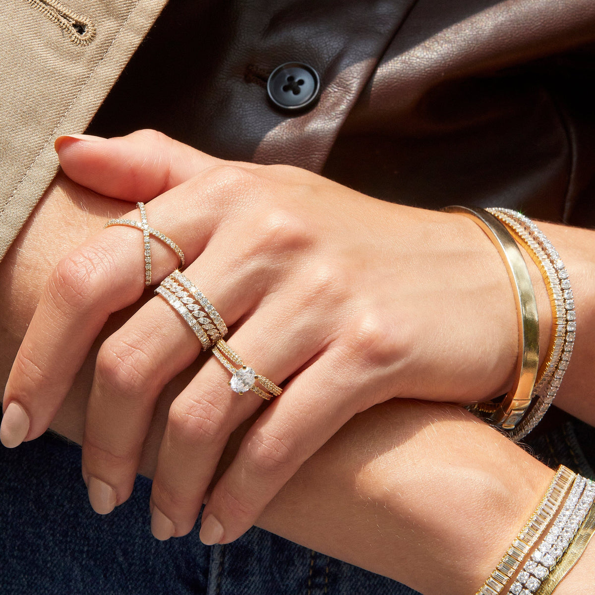 Lifestyle Model Close-up of a woman's crossed hands, wearing multiple gold and diamond rings and bracelets