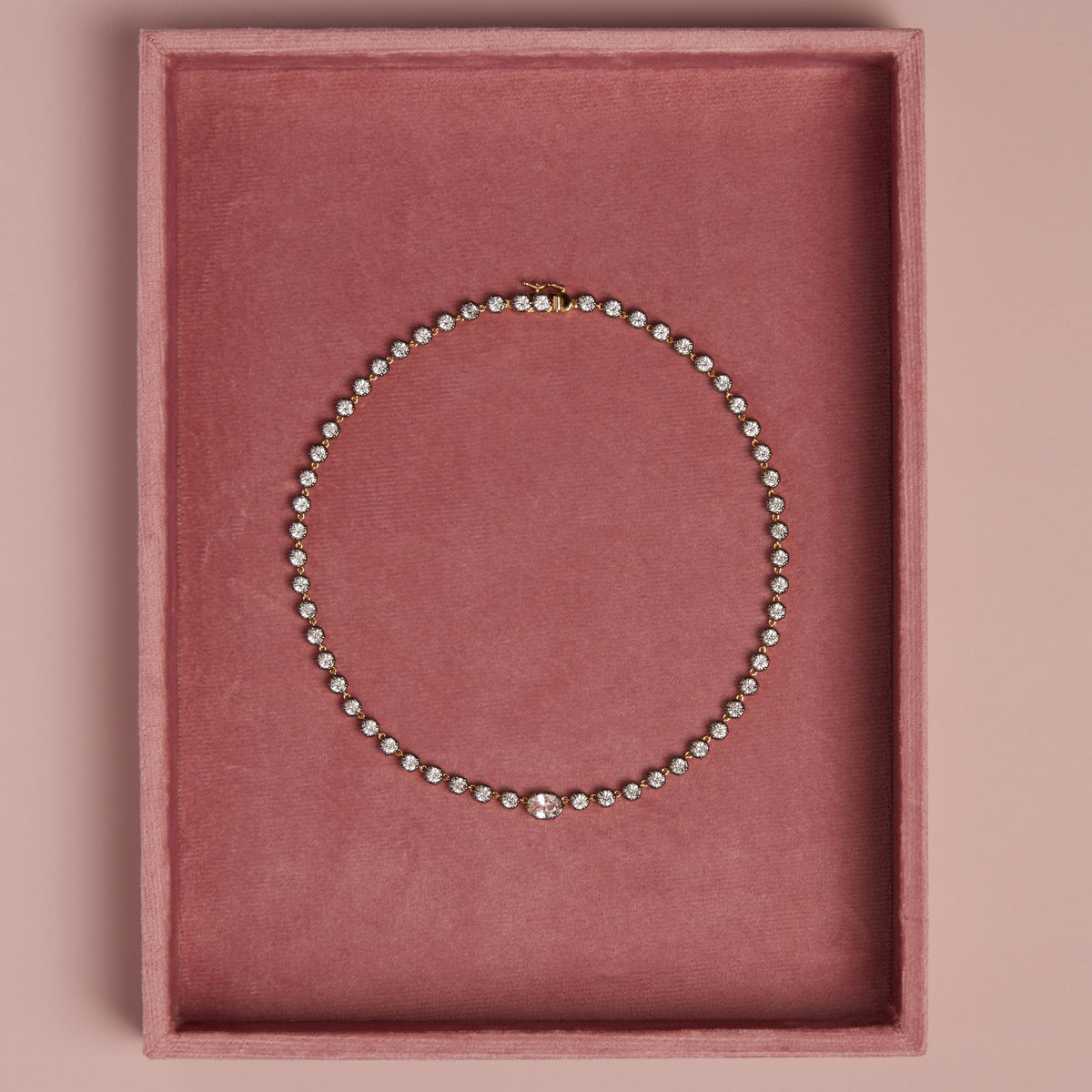 Model. Close up of tennis necklace in pink velvet holder. 