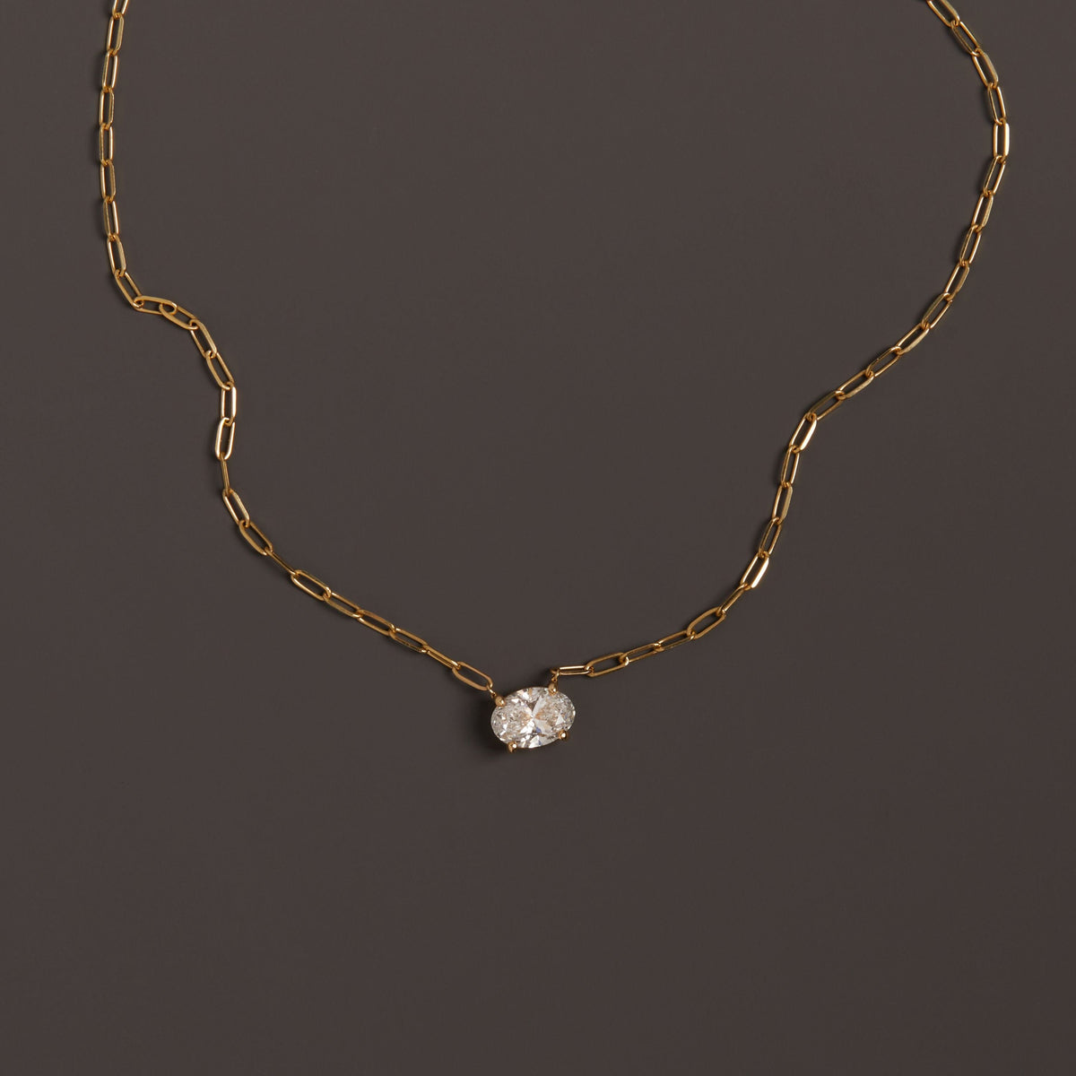 Model. Close up of diamond solitaire necklace on brown background.