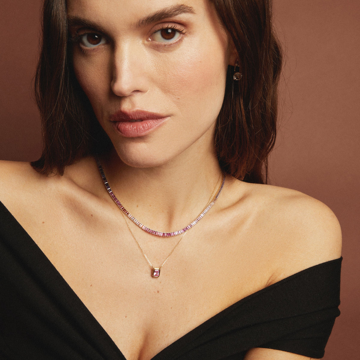Model. Woman wearing a delicate necklace against a brown background