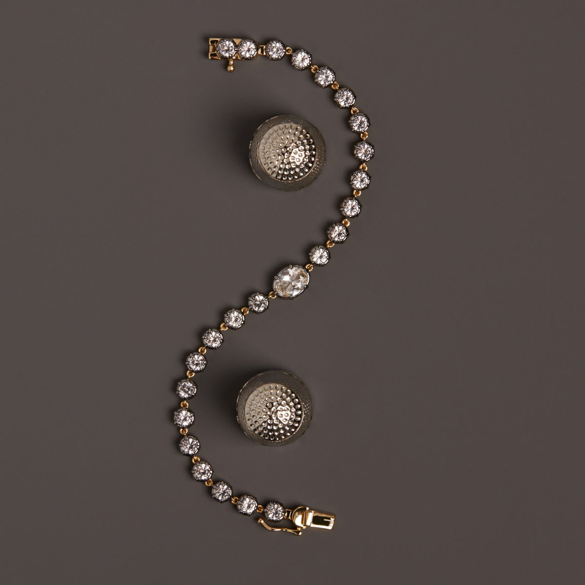Model. Close up of gemstone tennis bracelet on brown background.