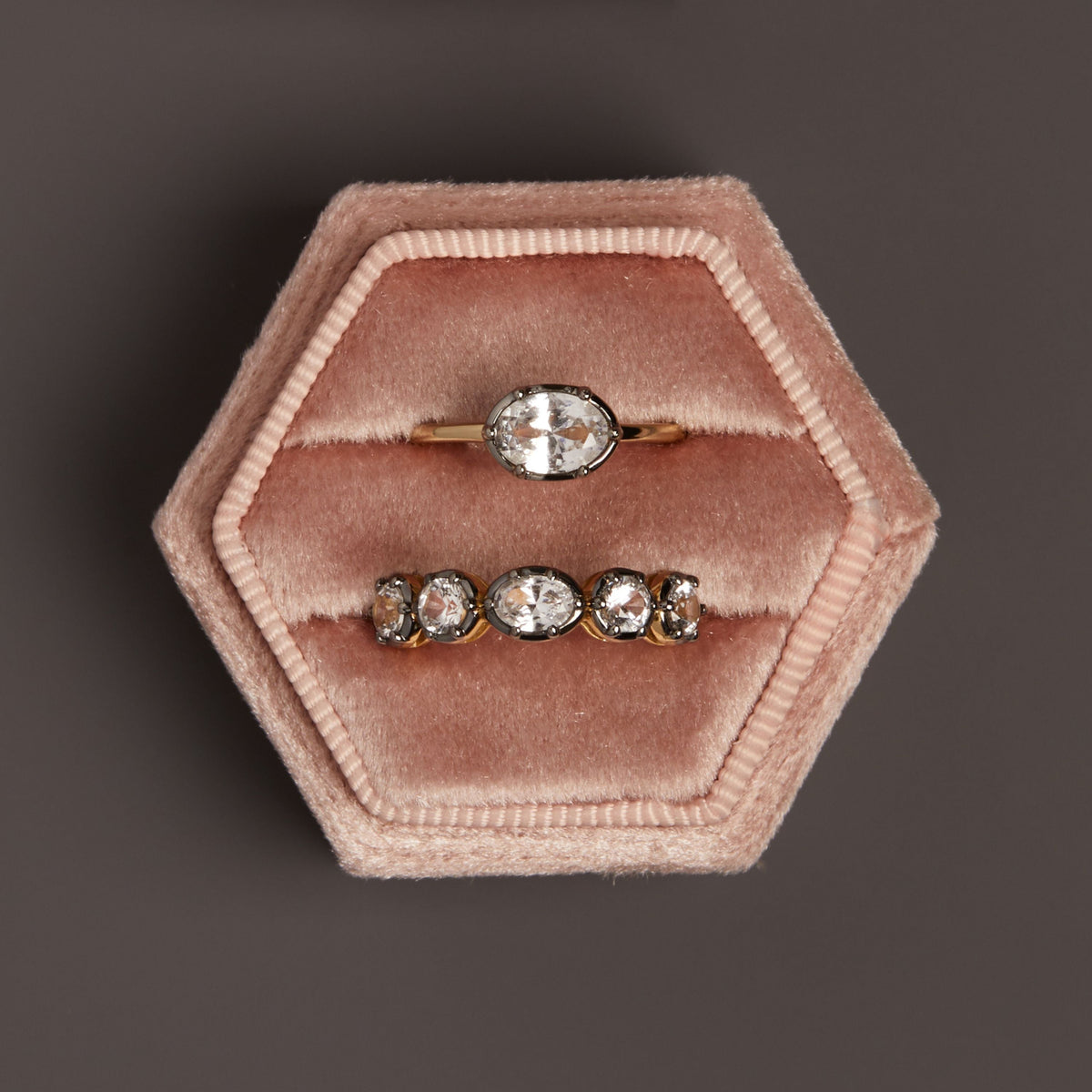 Model. Close up of two gemstone rings in ring holder. 