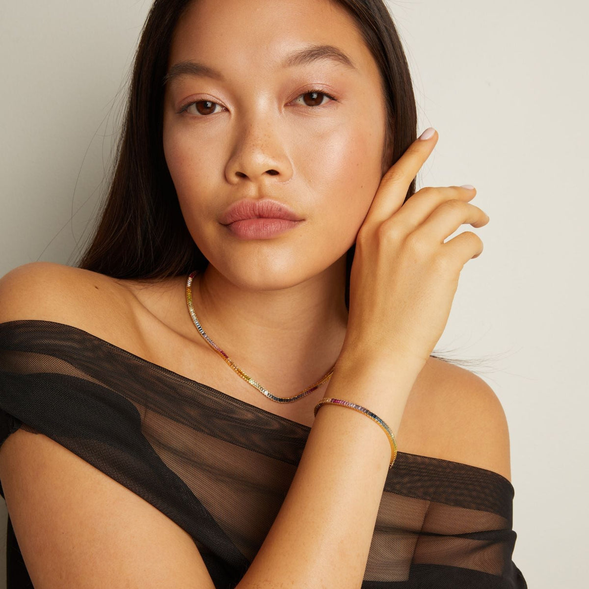 Model. Woman wearing a black sheer top with a neutral background