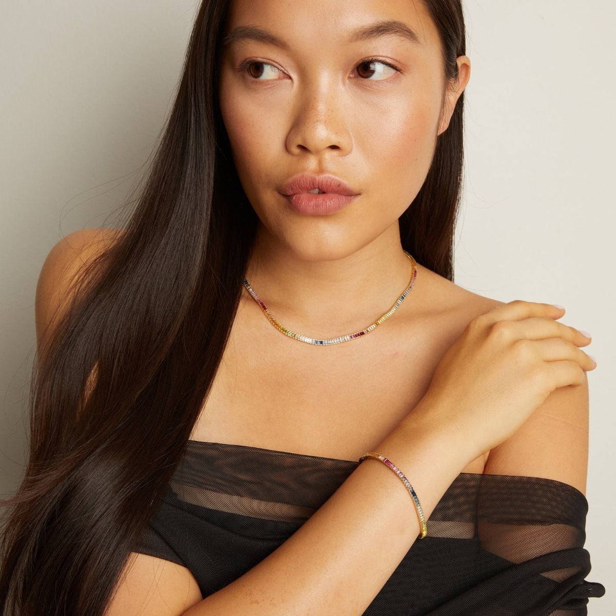 Model. Woman wearing a black sheer top with a neutral background