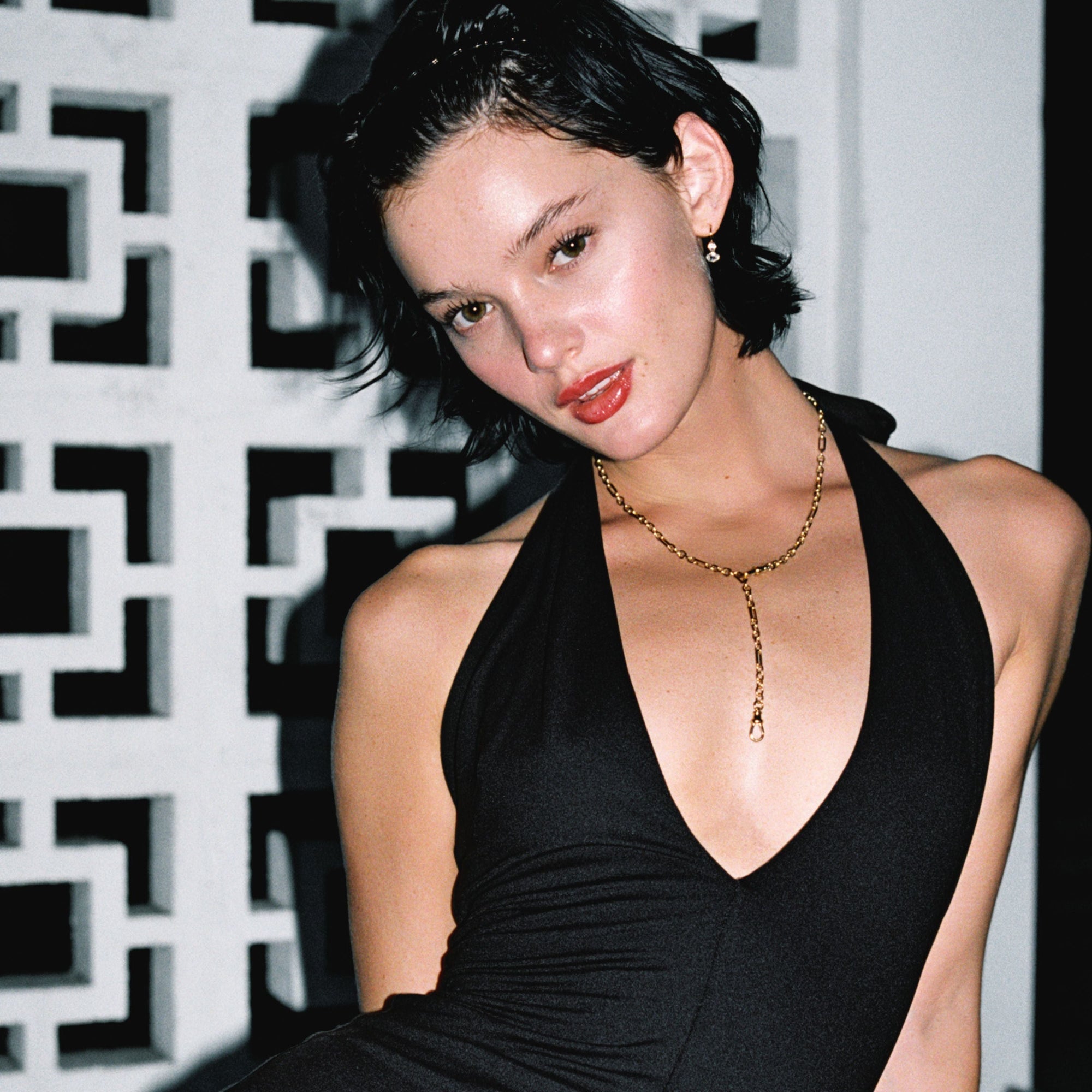 Model. Close up of woman wearing a gold chain necklace and a black dress