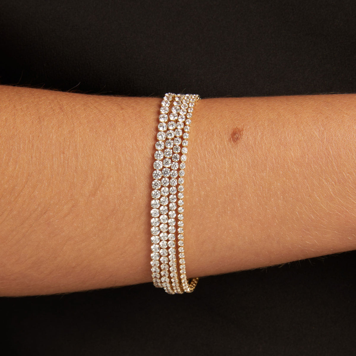 Model. Close up of a woman's wrist with four dainty diamond tennis bracelets. 