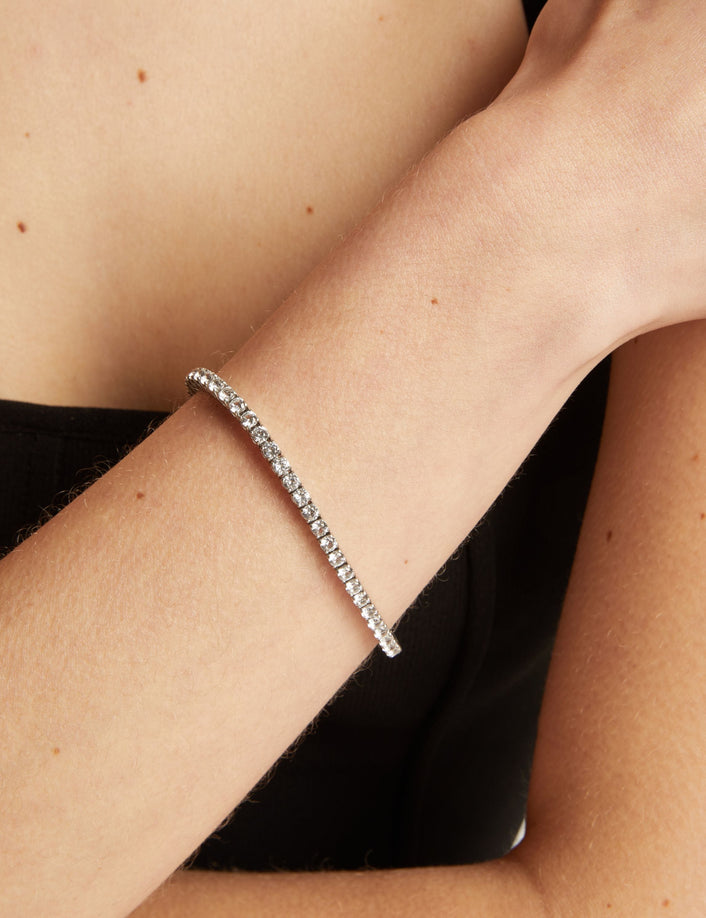 Tennis bracelet on a wrist with a black top.