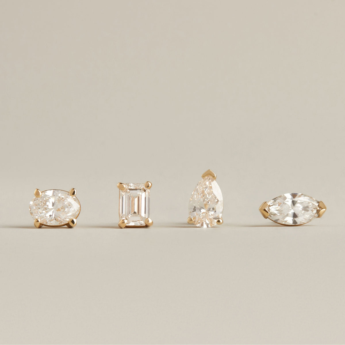 Model. Four different shape diamond stud earrings on neutral background