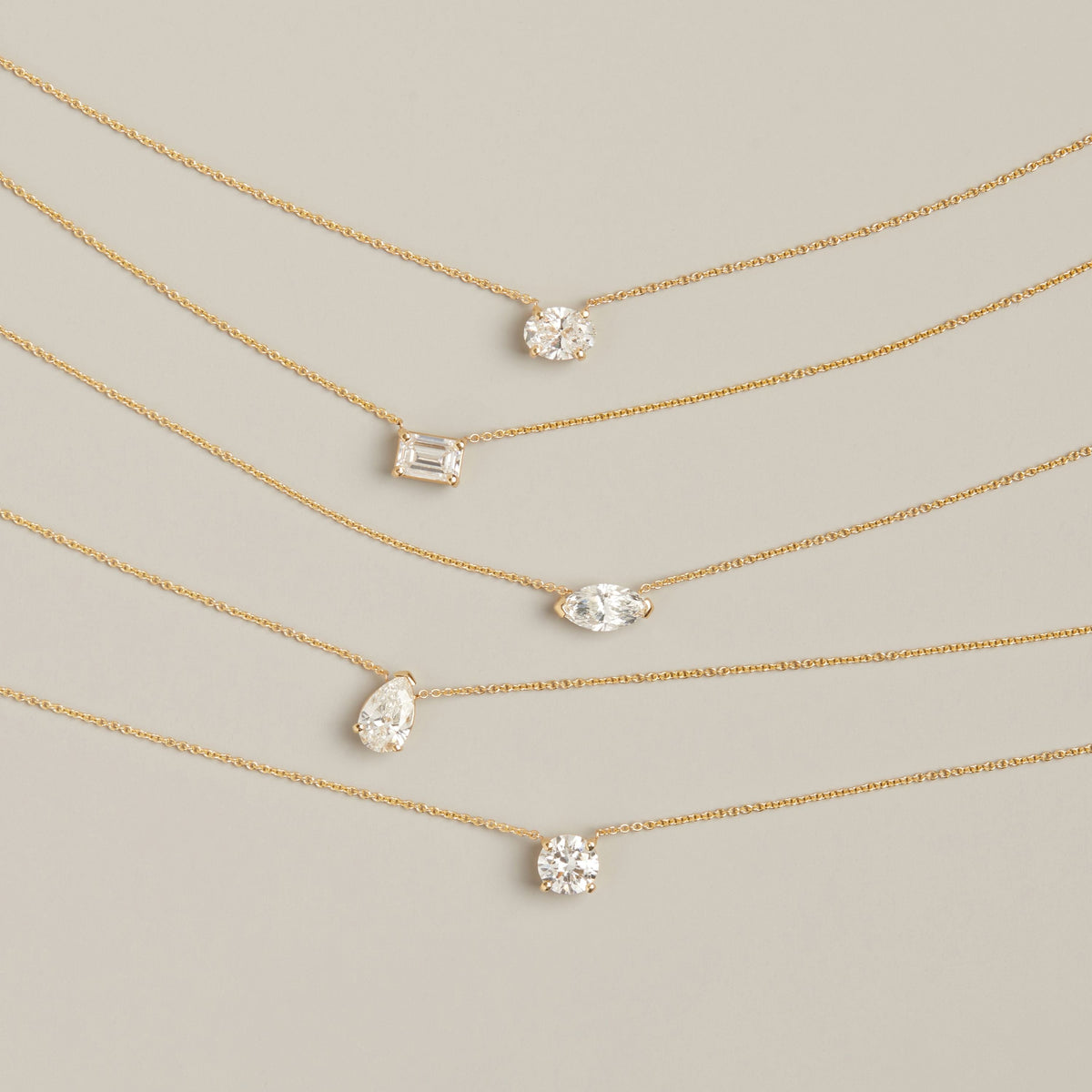 Model. Five gold chain necklaces with different shaped diamonds on neutral background