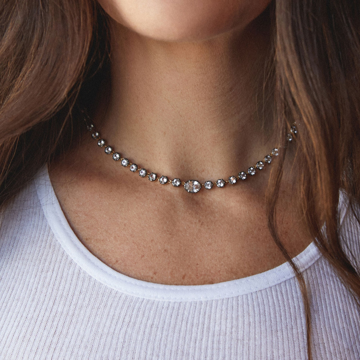 Model. Close up of a woman in a white top wearing a Georgian set tennis necklace.
