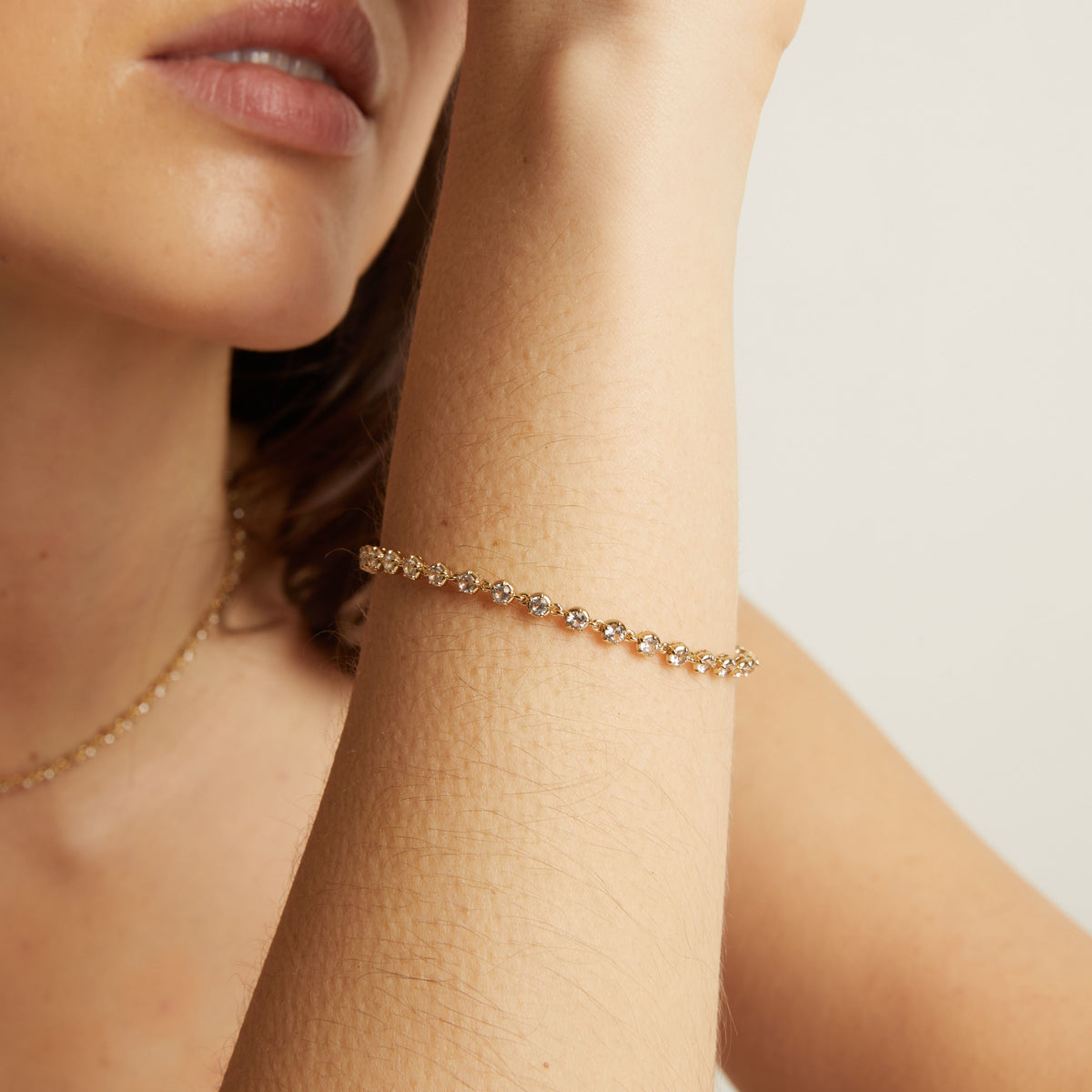 Model Close-up of a person wearing a delicate bracelet on a plain background