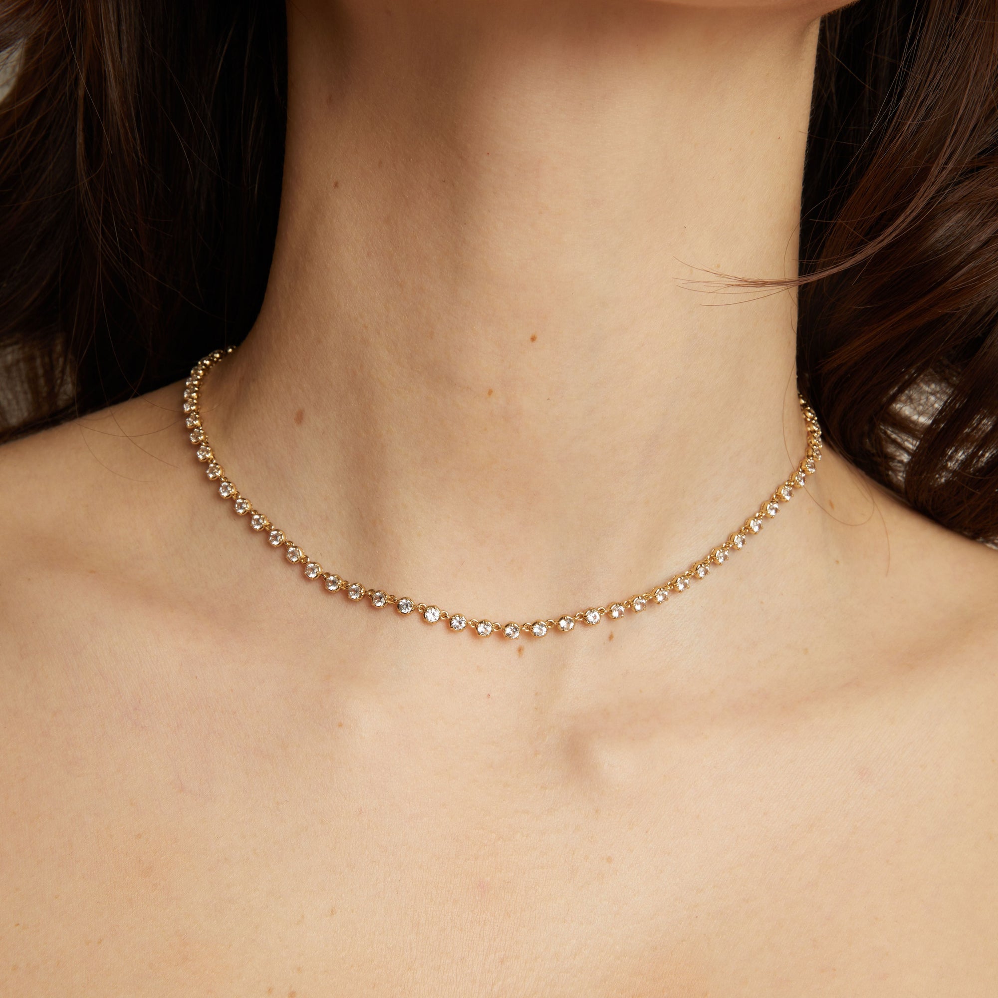 Gold necklace on a person's neck with a dark background