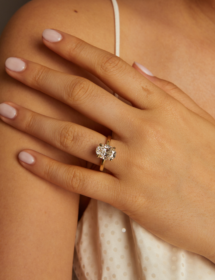 Hand wearing a diamond ring on a neutral background