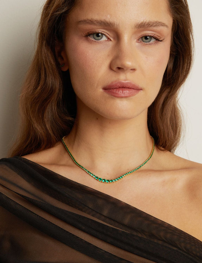 Model. Woman wearing a green beaded necklace against a neutral background