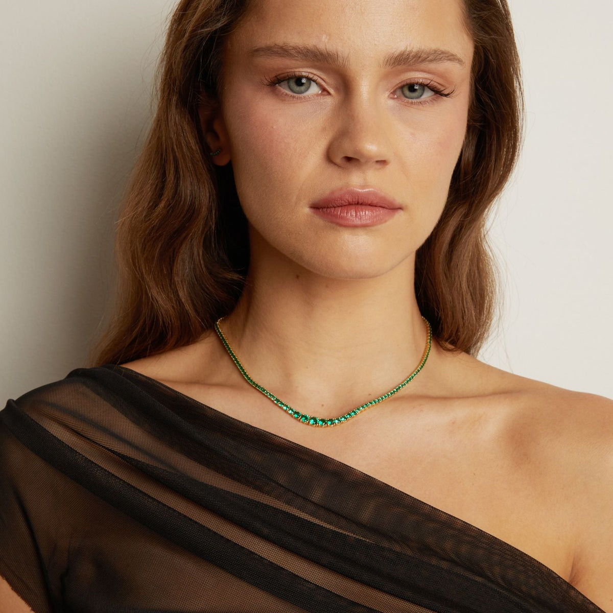 Model. Woman wearing a green beaded necklace against a neutral background