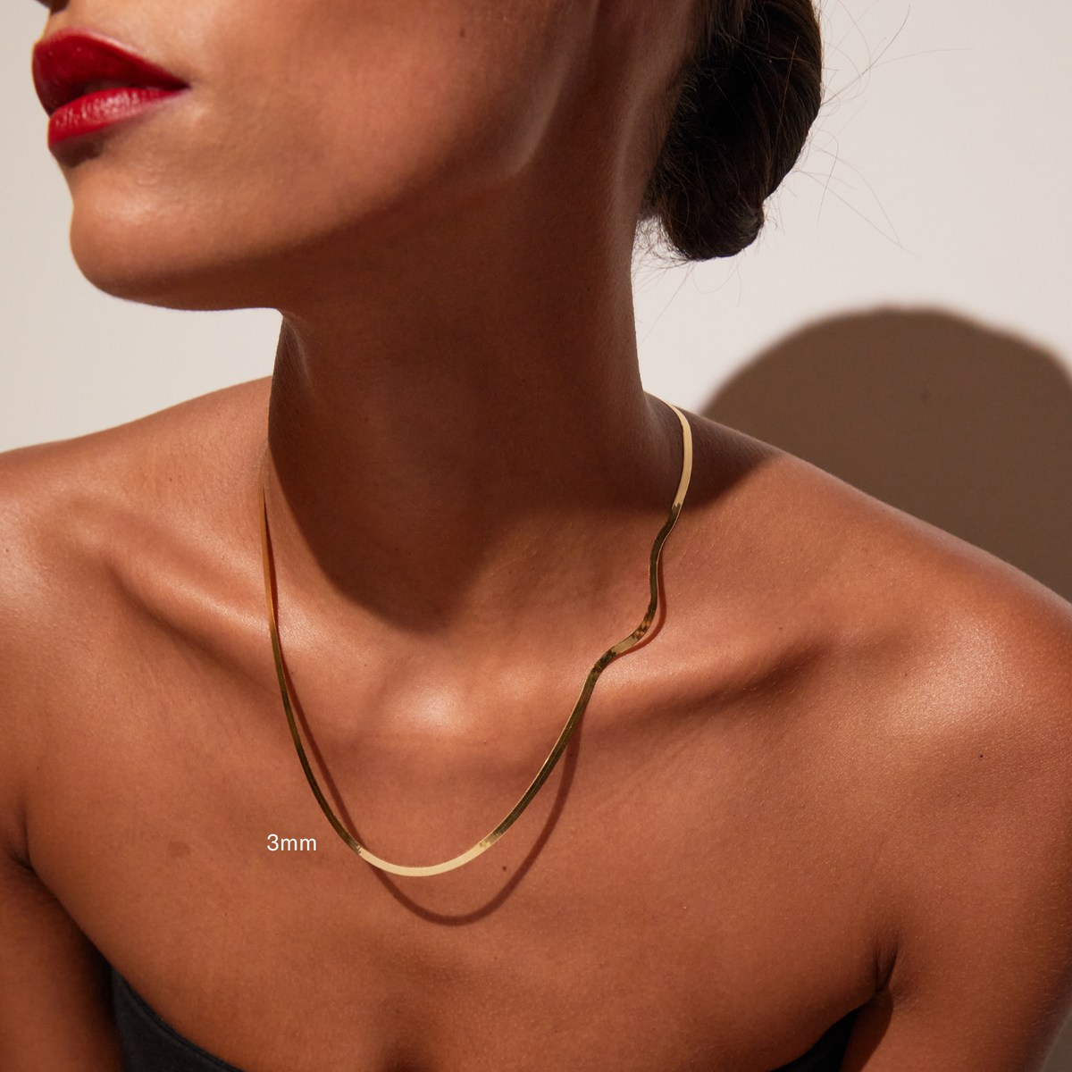 Model. Close up of woman wearing one gold herringbone chain necklace