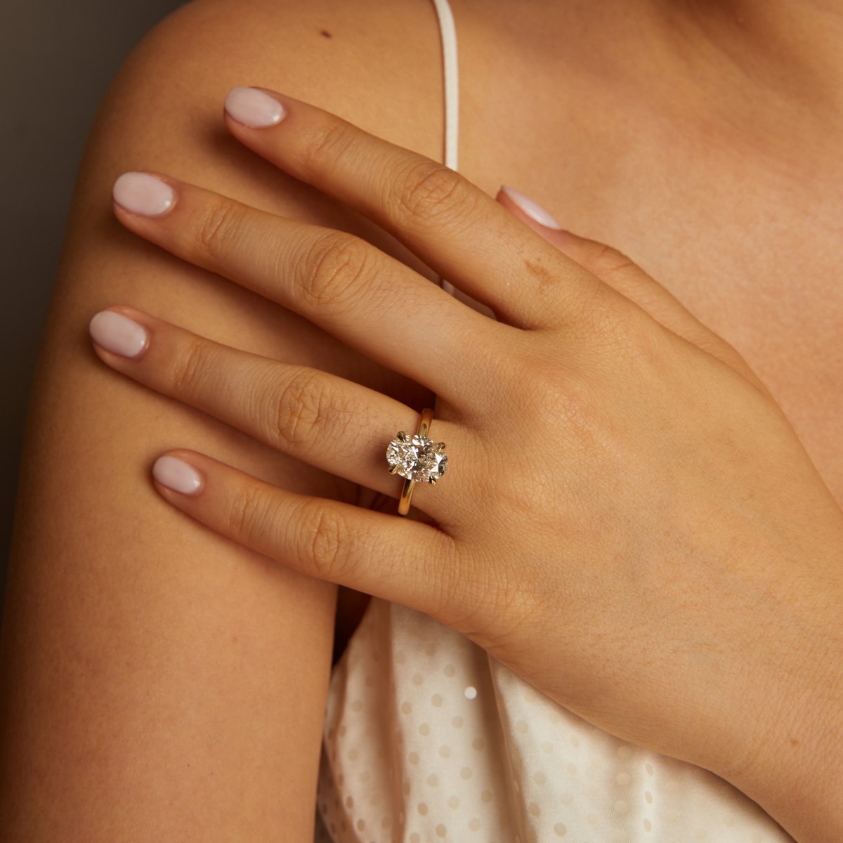 Model. Hand wearing a diamond ring on a neutral background