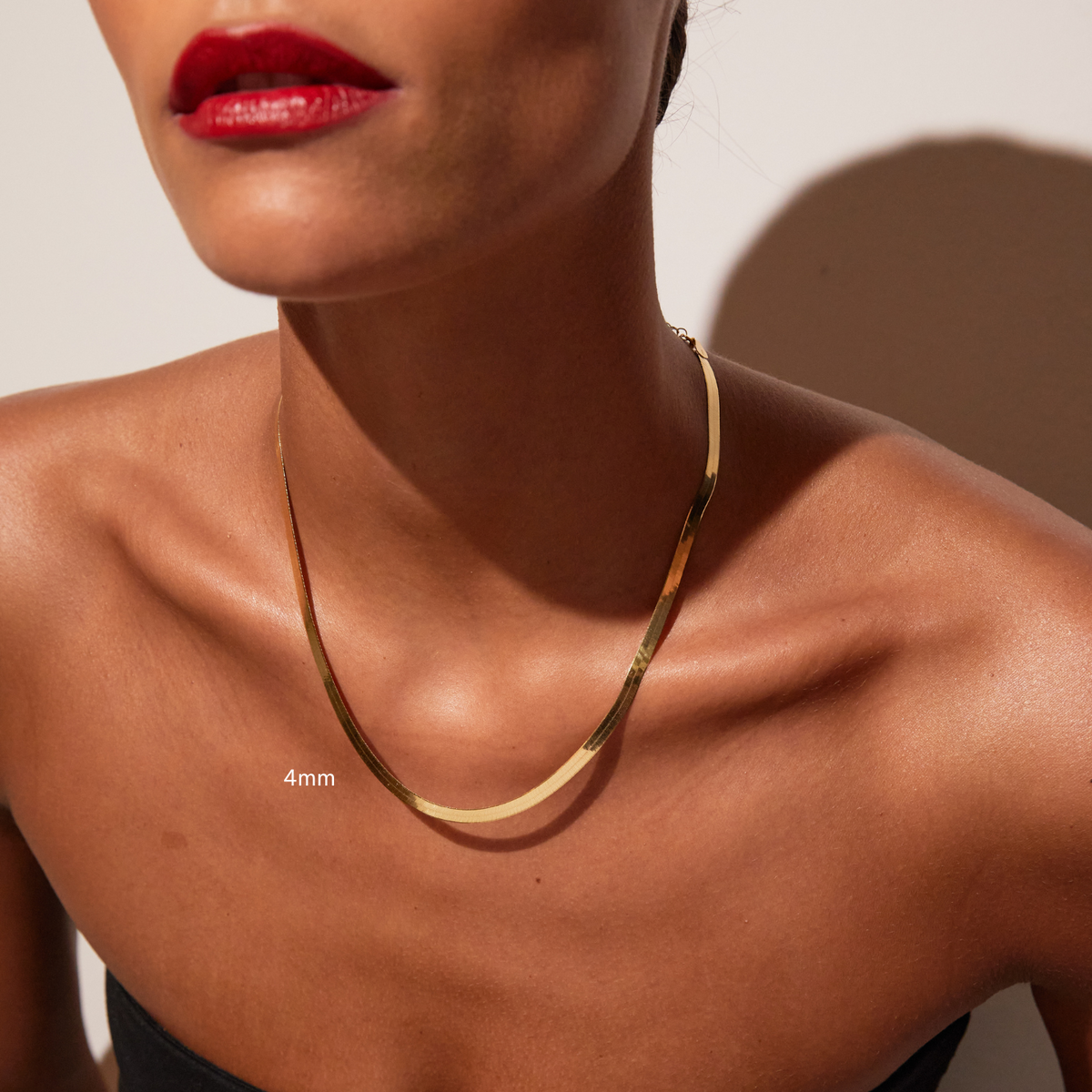 Model. Close up of woman wearing one gold herringbone chain necklace