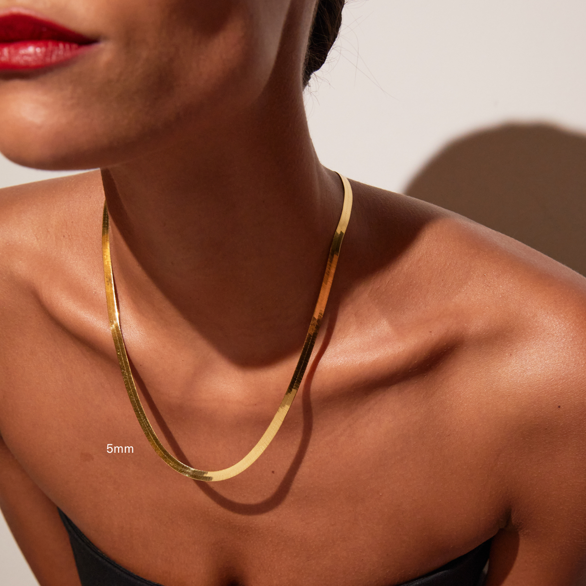 Model. Close up of woman wearing one gold herringbone chain necklace
