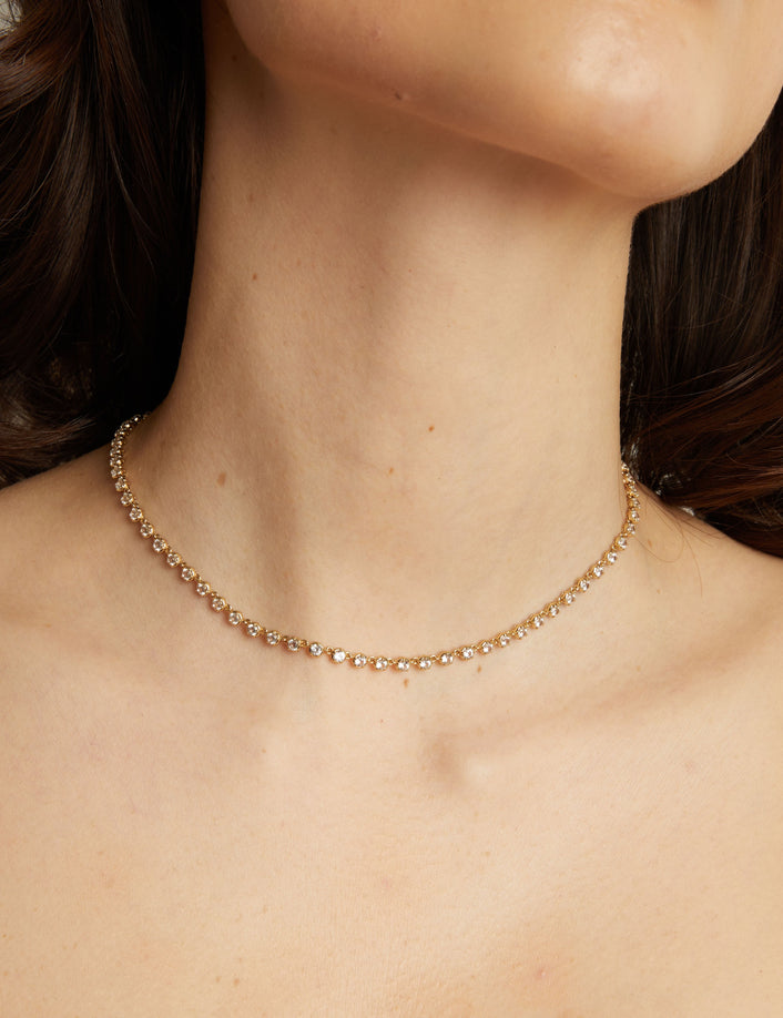 Gold necklace on a person with a neutral background