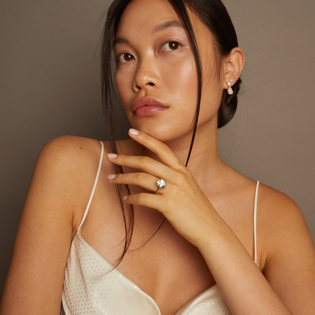 Model. Woman wearing a white lace top with a neutral background