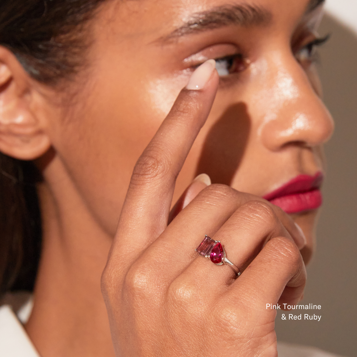 Model Close-up of a woman wearing a white gold two-stone ring with a pink and a red gemstone.
